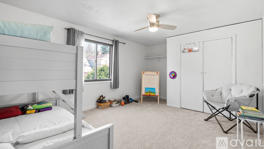 A bedroom with a white bed, a chair, and a fan.