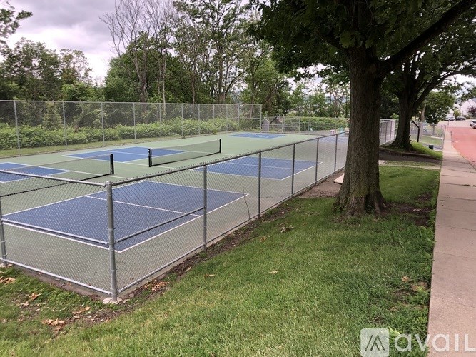 A tennis court surrounded by a fence and trees.