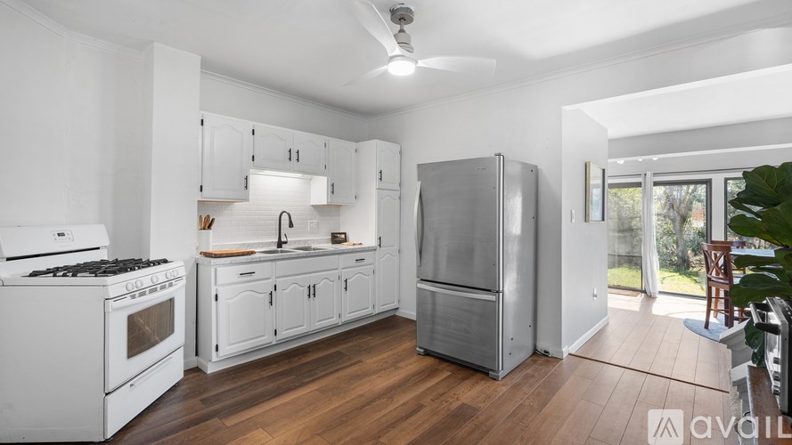 A modern kitchen with white appliances and wooden floors.