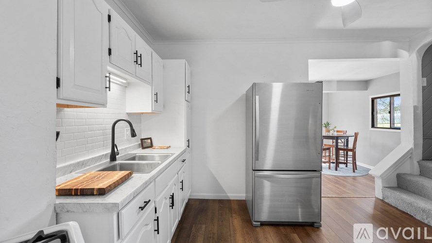 A kitchen with white cabinets and a stainless steel refrigerator.