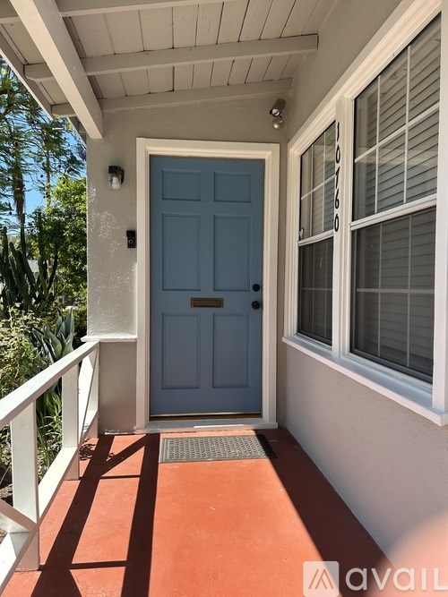 A blue door is on the left side of a white porch.