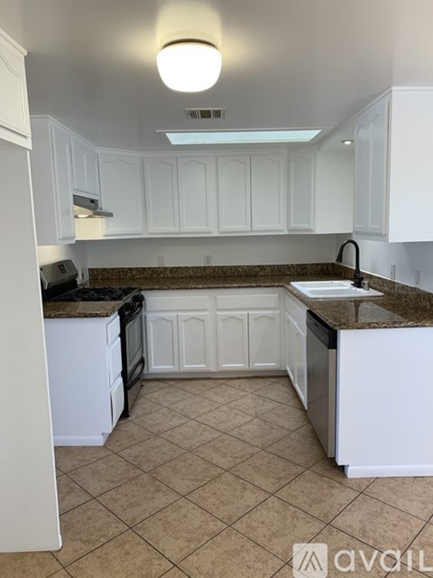 A kitchen with white cabinets and a granite countertop.