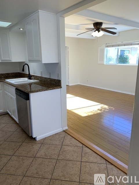 A kitchen with white cabinets and a brown countertop.
