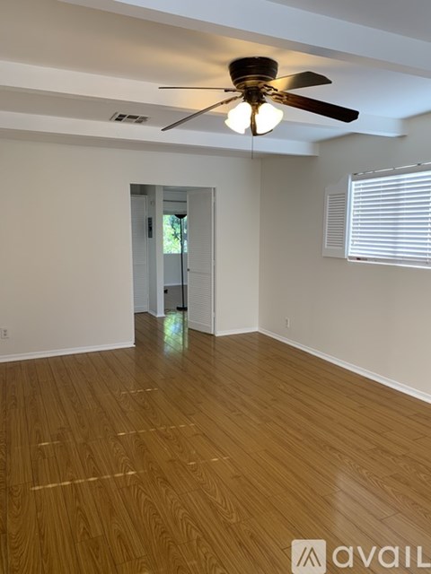 A room with wooden flooring and a ceiling fan.