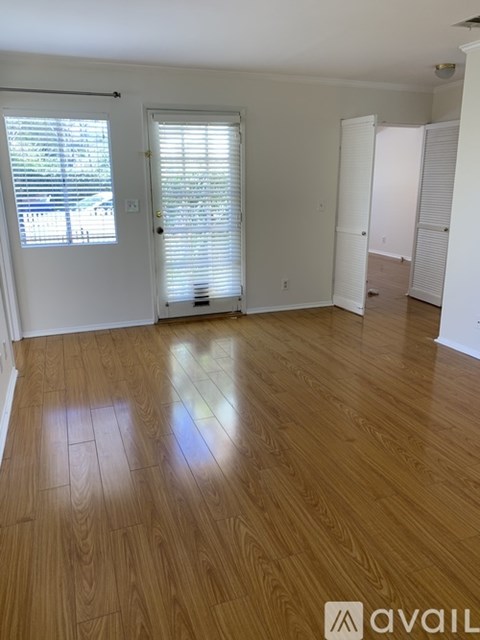 A room with wooden flooring and white walls.