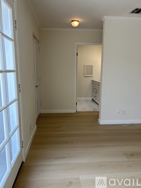 A room with wooden floors and a window with blinds.