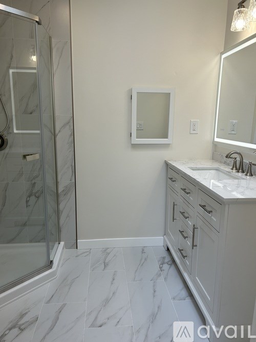 A bathroom with a marble floor and a walk-in shower.