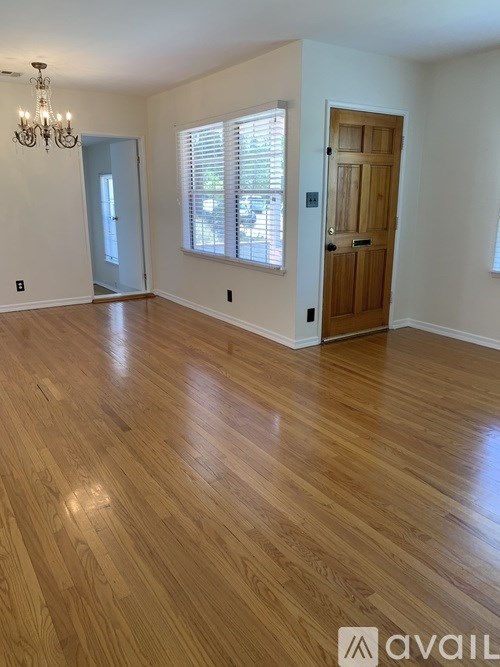 A room with wooden flooring and a chandelier.