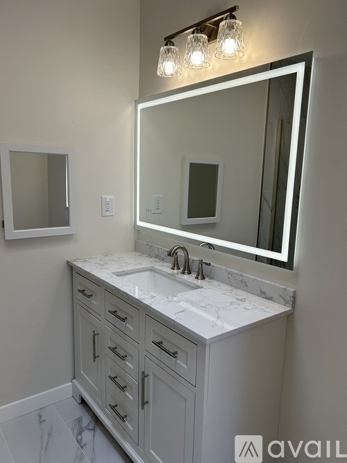 A bathroom vanity with a marble countertop and a large mirror above it.