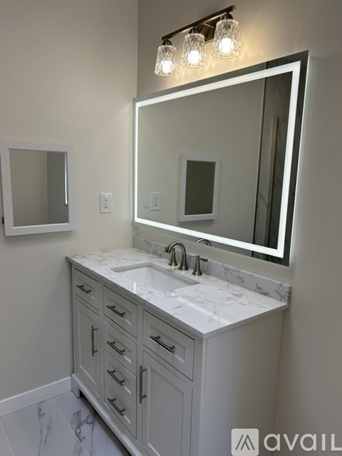 A bathroom vanity with a marble countertop and a large mirror above it.