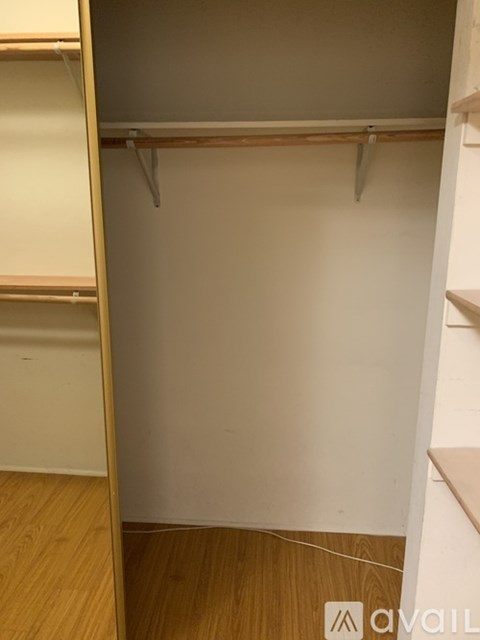 A small closet with a white door and a wooden floor.