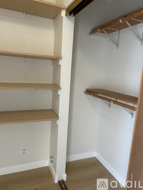 A white wall with a shelf and a clothes hanger.