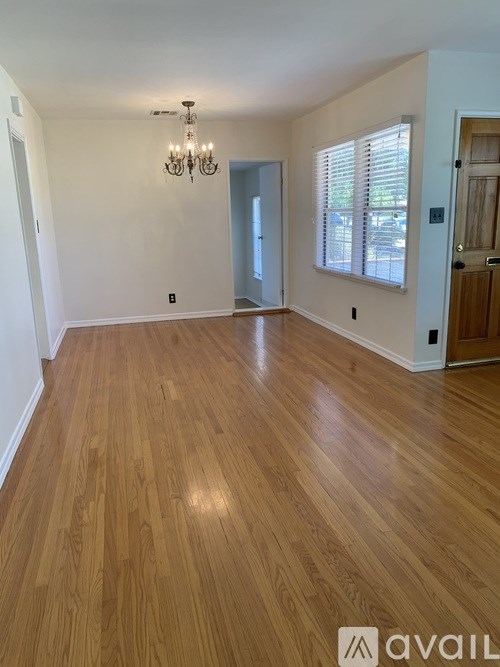 A room with wooden flooring and a chandelier.