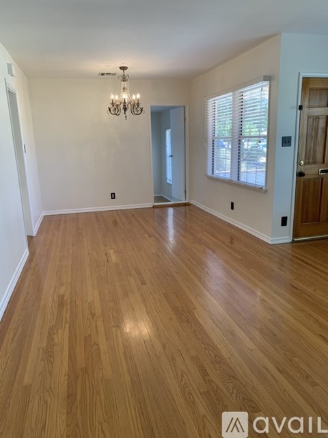 A room with wooden flooring and a chandelier.