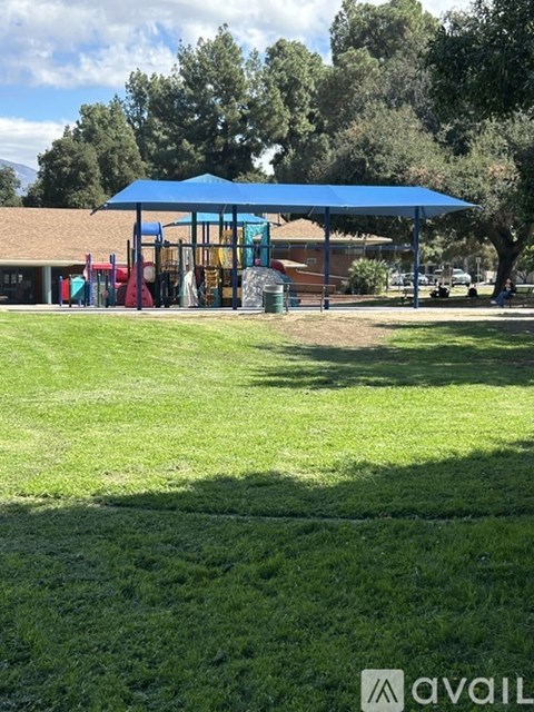 A playground with a blue canopy and a red slide.