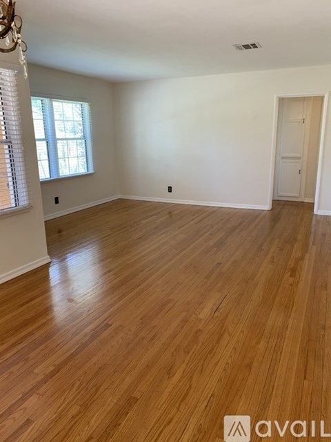 A room with wooden flooring and a window with blinds.