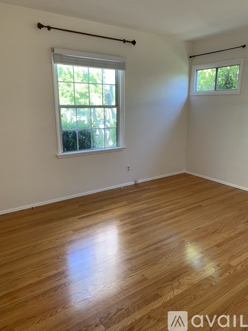 A room with wooden flooring and a window with blinds.