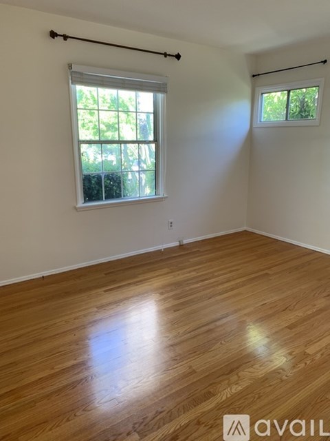 A room with wooden flooring and a window with blinds.