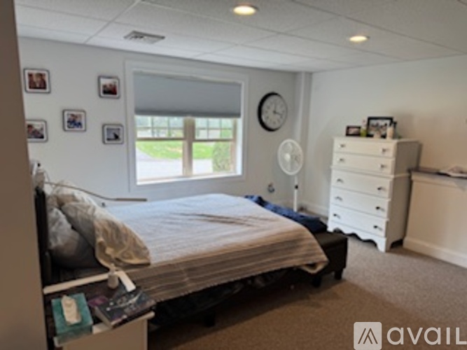 A bedroom with a bed, dresser, and window with blinds.