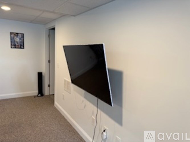 A black screen is mounted on a white wall.