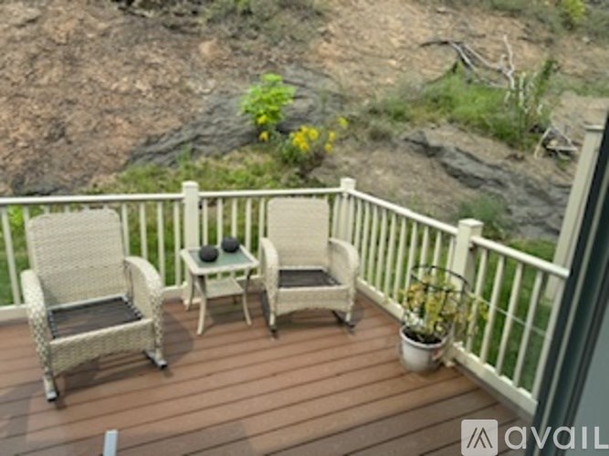 A balcony with chairs and a table overlooking a rocky landscape.