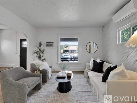 A living room with a grey couch, a grey armchair, a black coffee table, and a white sofa with a mirror on the wall.