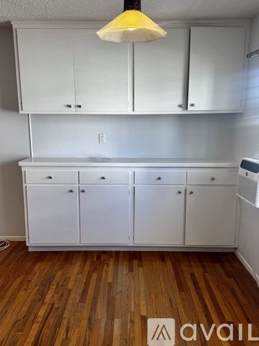 A kitchen with white cabinets and a wooden floor.