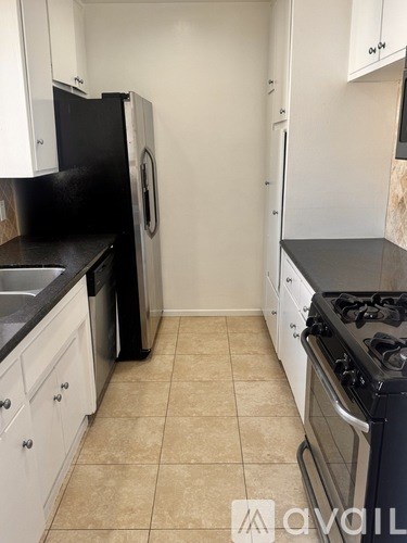 A kitchen with black appliances and white cabinets.