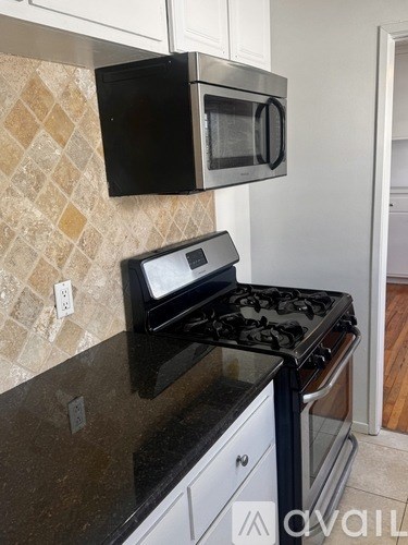 A black microwave oven is mounted above a black gas stove.