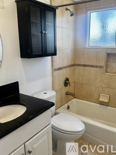 A bathroom with black and white fixtures and a black cabinet.