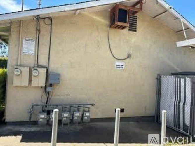 A building with a fence and electrical boxes on the wall.
