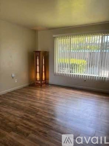 A room with wooden floors and a window with blinds.