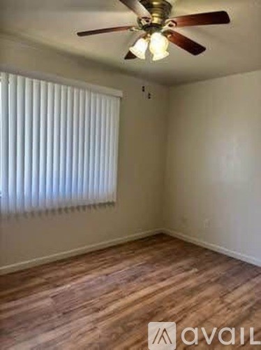 A room with a ceiling fan and wooden flooring.