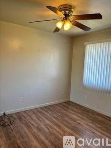 A room with a ceiling fan and wooden flooring.