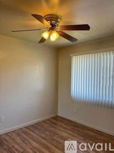 A room with a ceiling fan and a window with blinds.