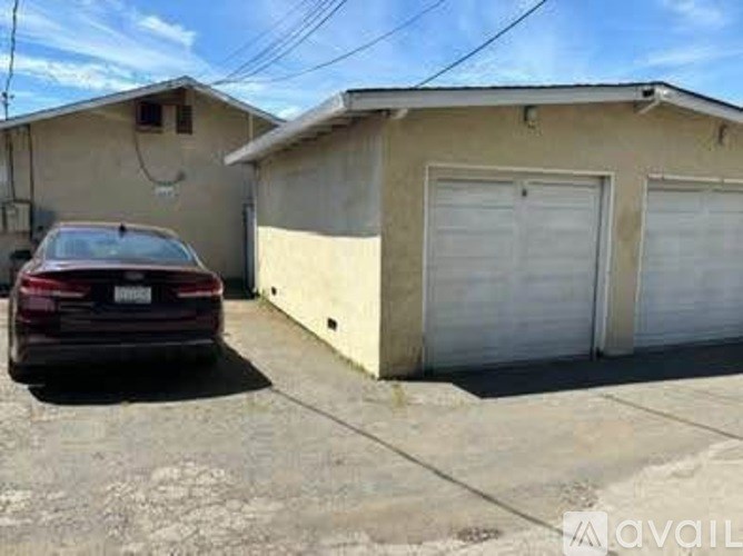 A red car is parked in front of a garage.
