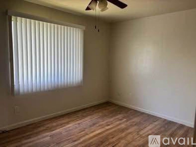 A room with a ceiling fan and a window with blinds.