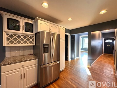 A kitchen with a stainless steel refrigerator and wooden floors.