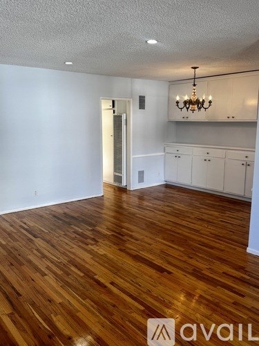 A room with wooden flooring and a chandelier.