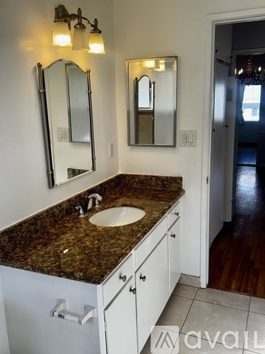 A bathroom with a granite countertop and two mirrors.