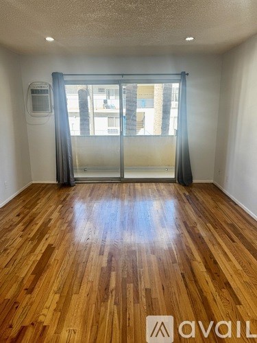 A room with wooden flooring and a sliding glass door.