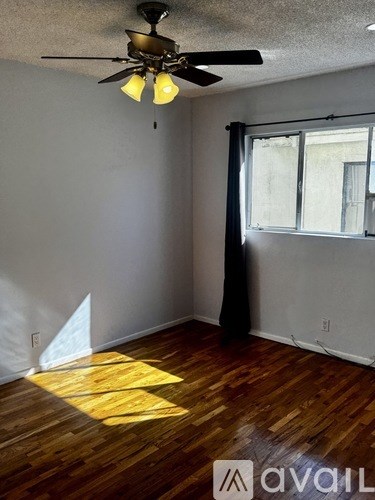 A room with a ceiling fan and wooden flooring.