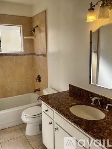 A bathroom with a brown granite countertop and white fixtures.