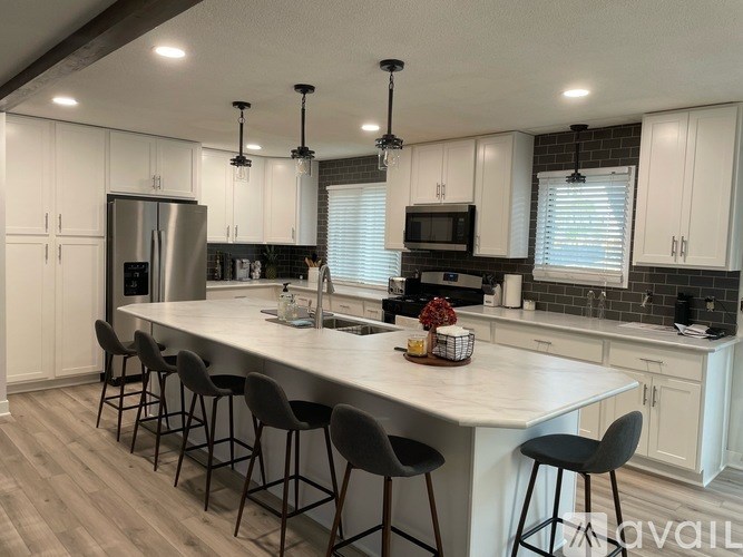 A kitchen with a white island and bar stools.