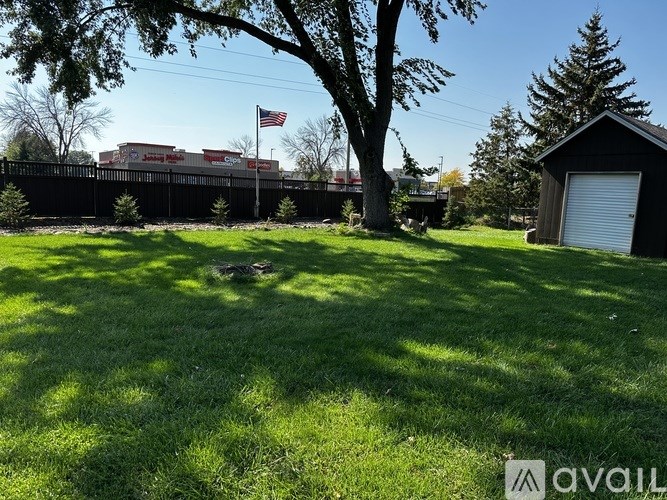 A grassy area with a tree and a building in the background.
