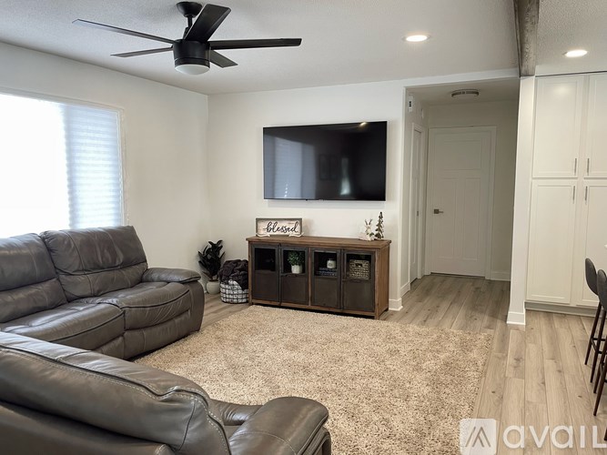 A living room with a grey leather sofa and a wooden cabinet with glass doors.