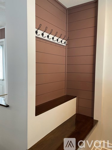 A wooden bench with a coat rack above it.