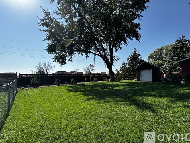A backyard with a fence, a tree, and a house in the background.