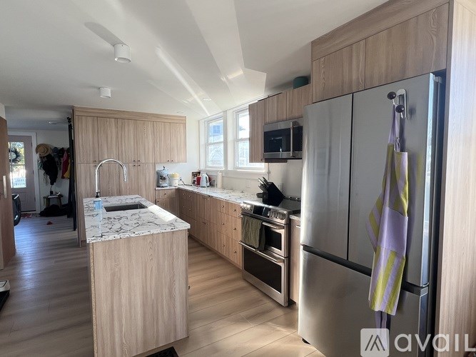 A kitchen with wooden cabinets and a marble island.
