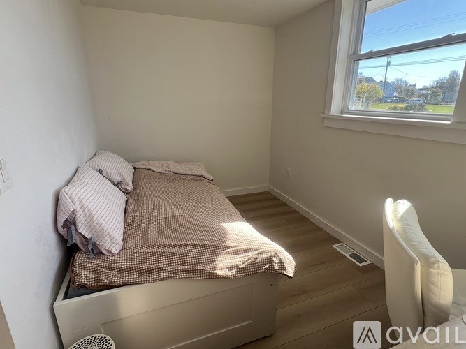 A bedroom with a bed, a chair, and a window.